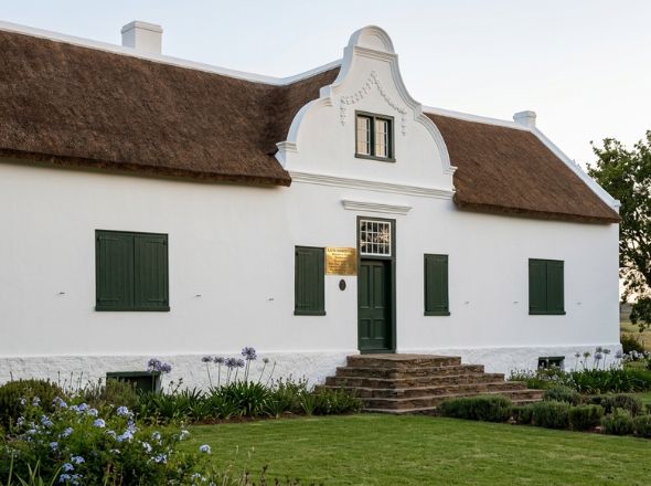 Traditional Cape Dutch architecture commercial building featuring high-density thatched roofing and a historic decorative masonry wall gable