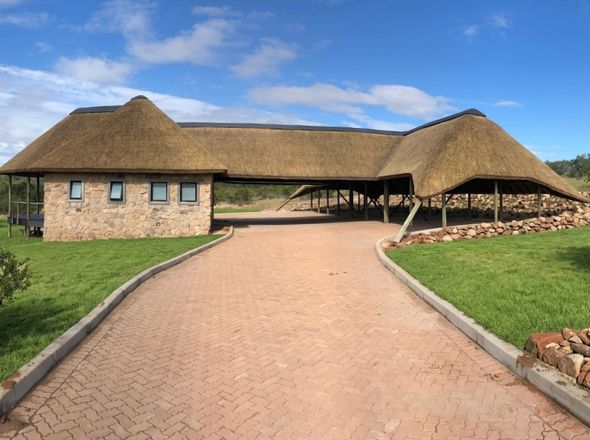 Large-scale commercial thatched roof installation and stone masonry construction for a luxury game reserve entrance and lodge facility