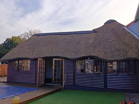 Projects Wooden log cabin entertainment room with a contoured thatch roof situated next to a wooden pool deck
